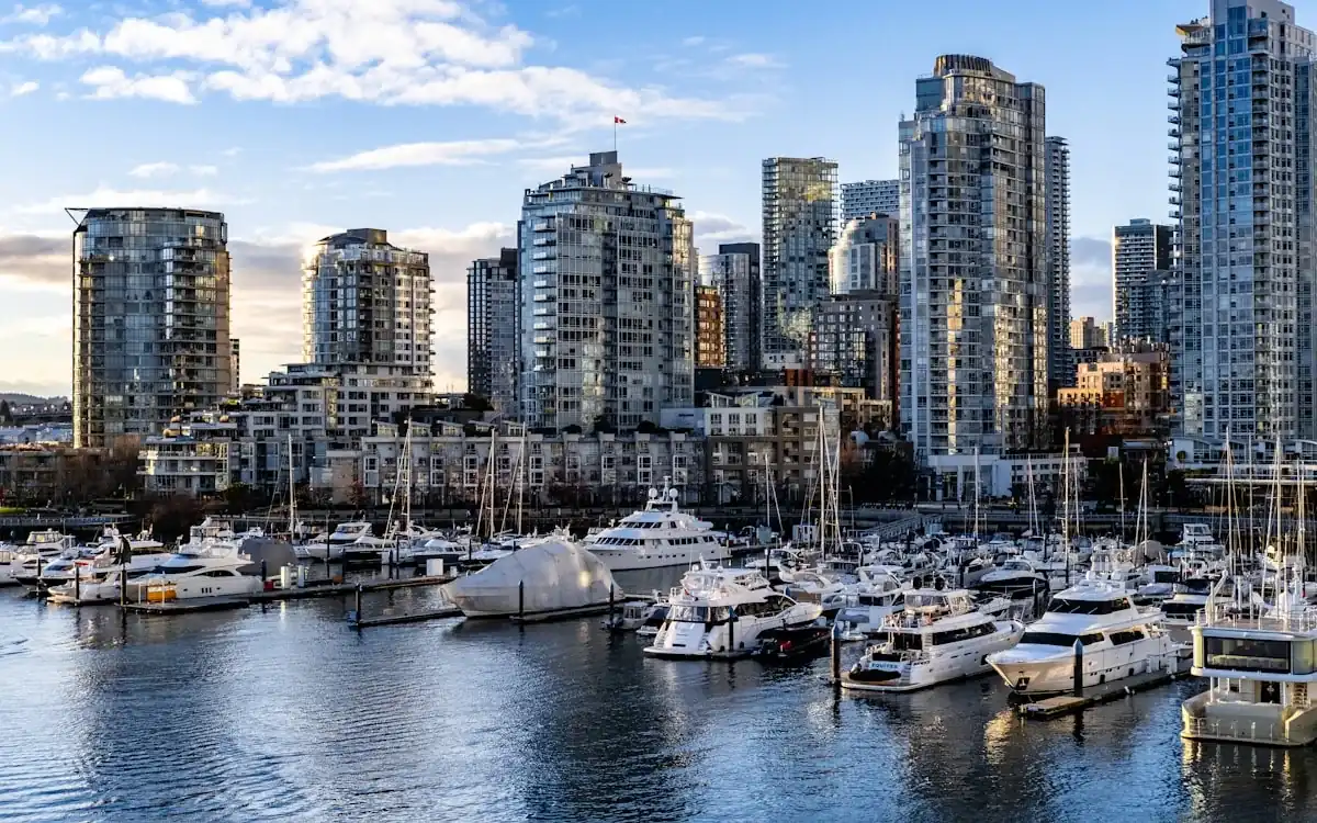 Waterfront marina with sailboats below city condo towers